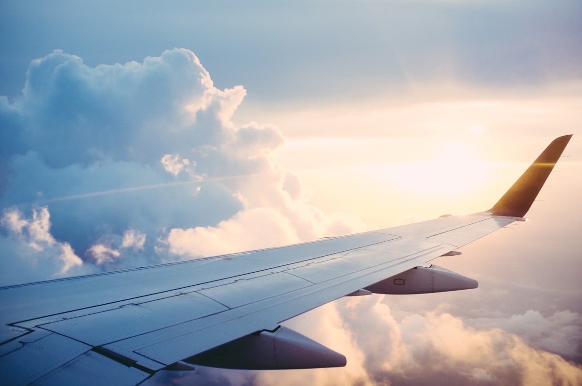 Commercial airplane wing above clouds at sunrise